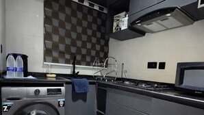 Una cucina compatta con lavatrice, lavello e fornello.