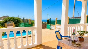 A terrace with a pool, a table with a bottle and glasses, and a view of the sea. - Cortijo las Flores con Piscina Privada (Torrox)