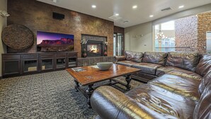 Un salón amplio con un sofá de cuero, una chimenea y un televisor grande.