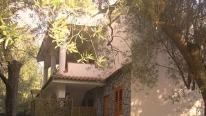 Una casa de dos pisos con fachada de piedra, un balcón y una puerta de madera.
