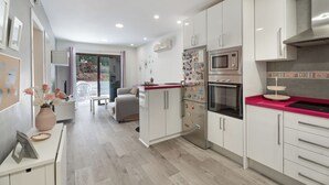 A modern kitchen with white cabinets, a red countertop, and a built-in microwave. - Charming 2-bedroom Apartment in Puerto de Santiago (Santiago del Teide)