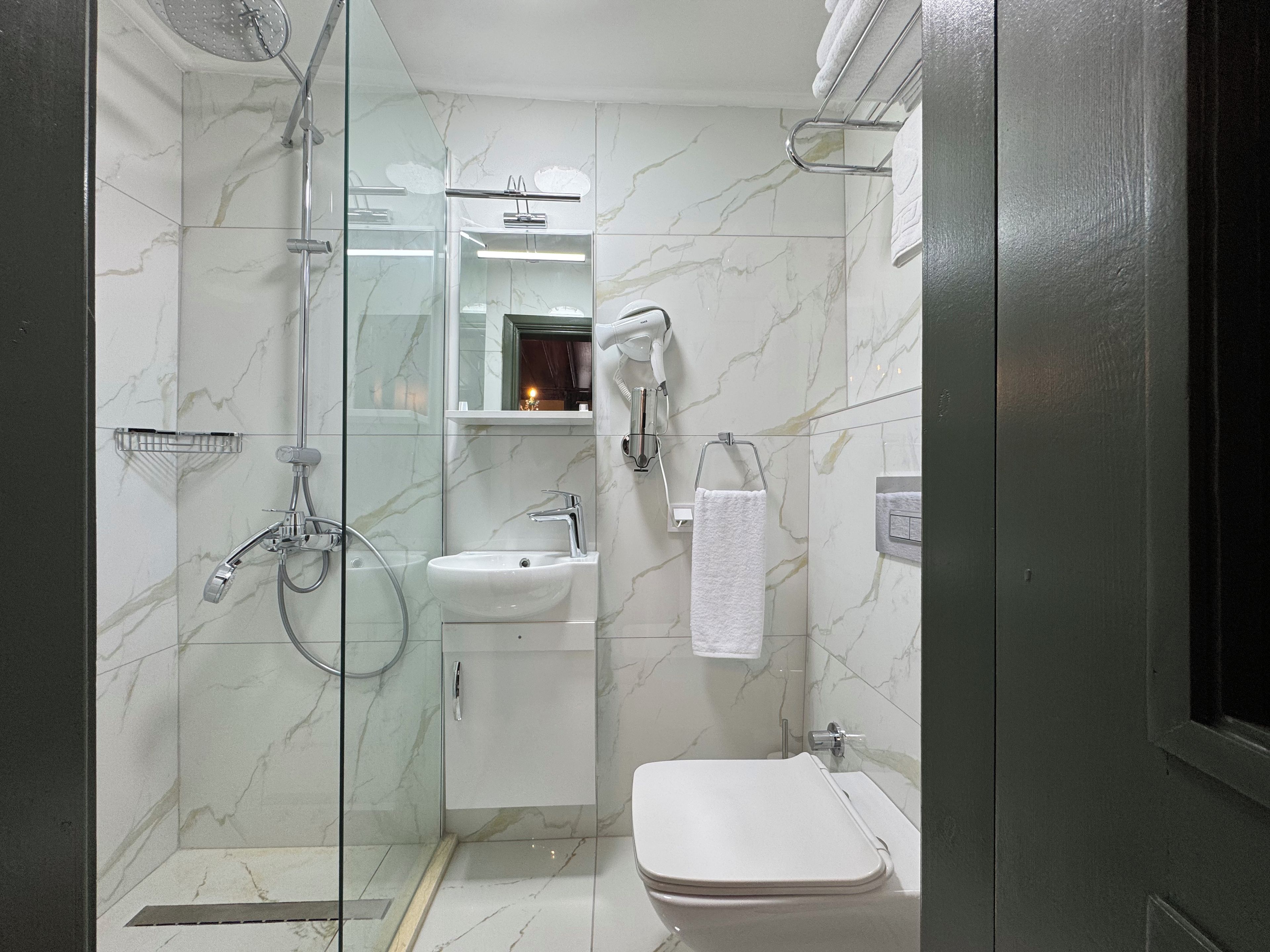 Un baño moderno con cabina de ducha de vidrio, un lavamanos blanco y un inodoro.