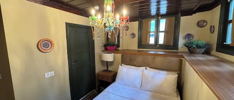 Un dormitorio con cama, candelabro, ventana y placas decorativas en la pared.