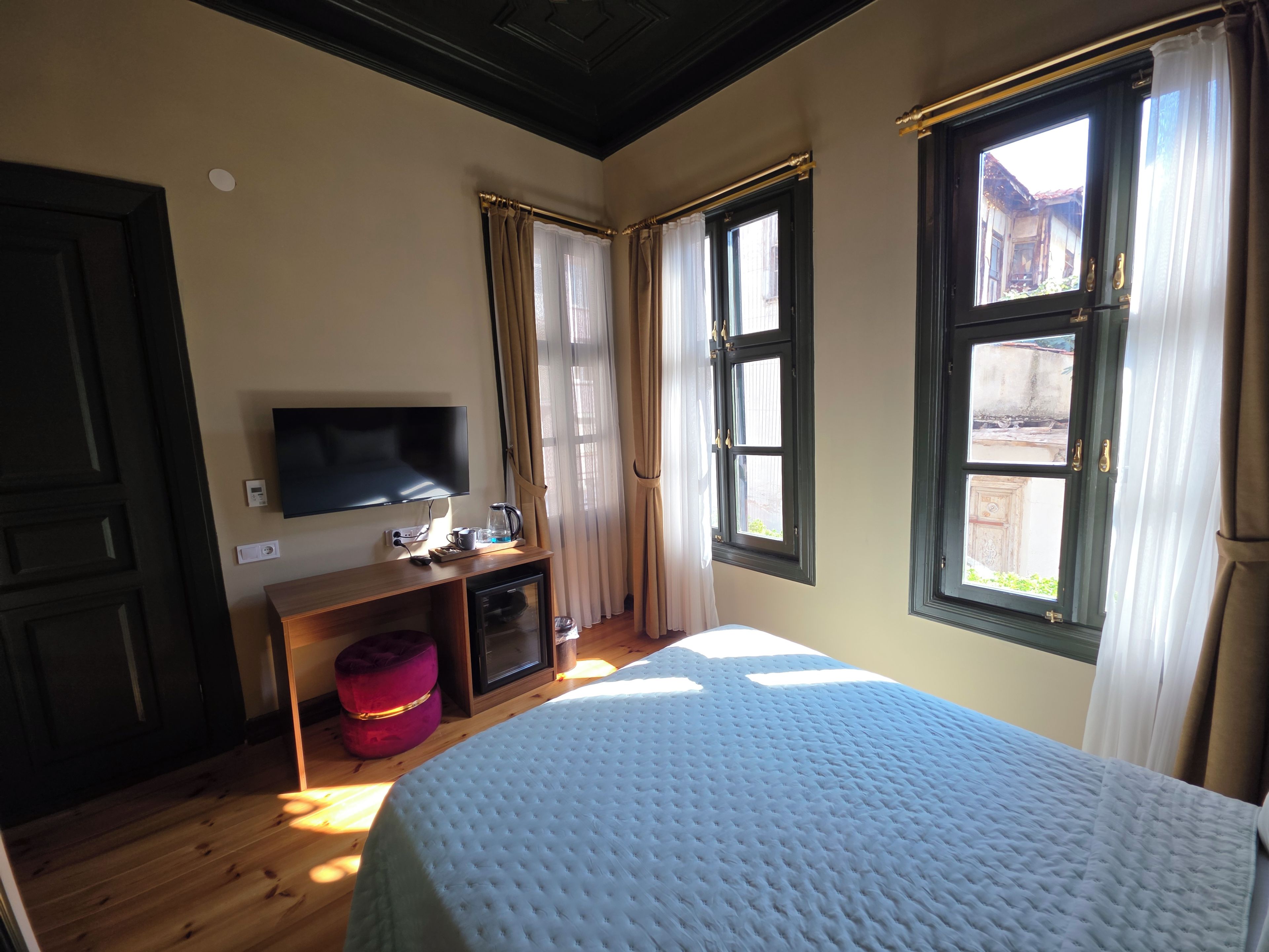 Una habitación de hotel con cama, televisión, cafetera y ventana con cortinas.