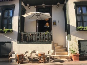 Un edificio con balcón, asientos al aire libre y una escalera que conduce a la entrada.