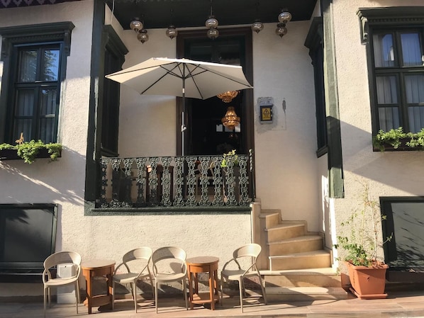 Un edificio con balcón, asientos al aire libre y una escalera que conduce a la entrada.