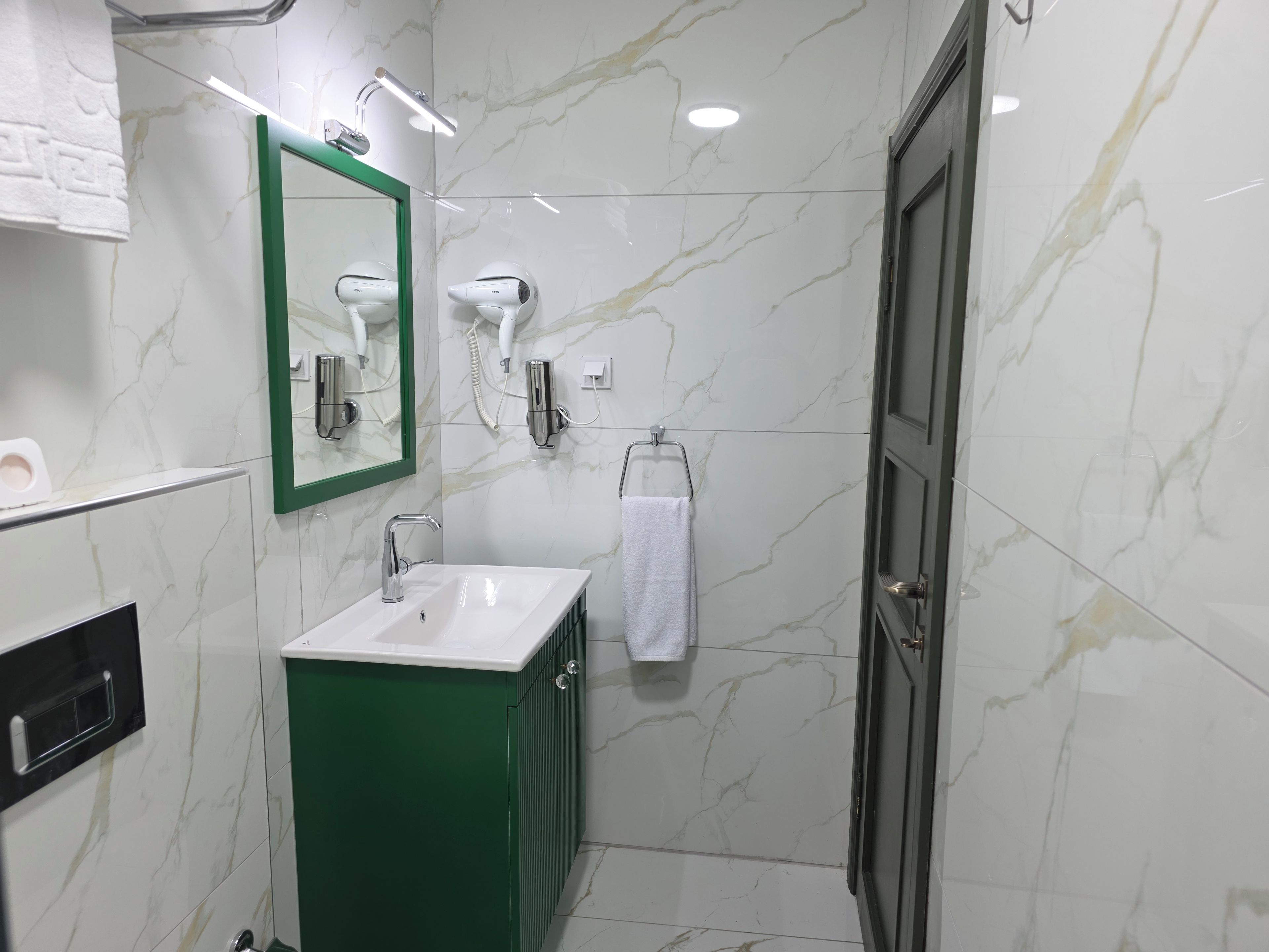A bathroom with a white sink, green cabinet, and a mirror.