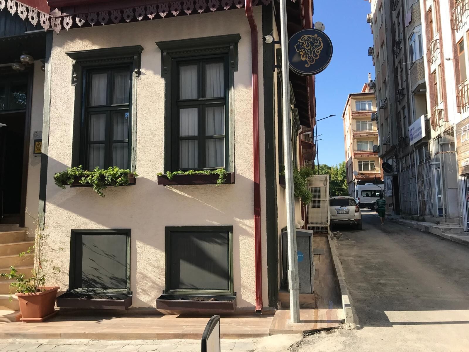 Um edifício com três janelas, uma porta e uma pequena varanda com plantas.