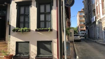 A building with three windows, a door, and a small balcony with plants.