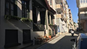 A narrow street lined with multi-story buildings, some with balconies and outdoor seating.