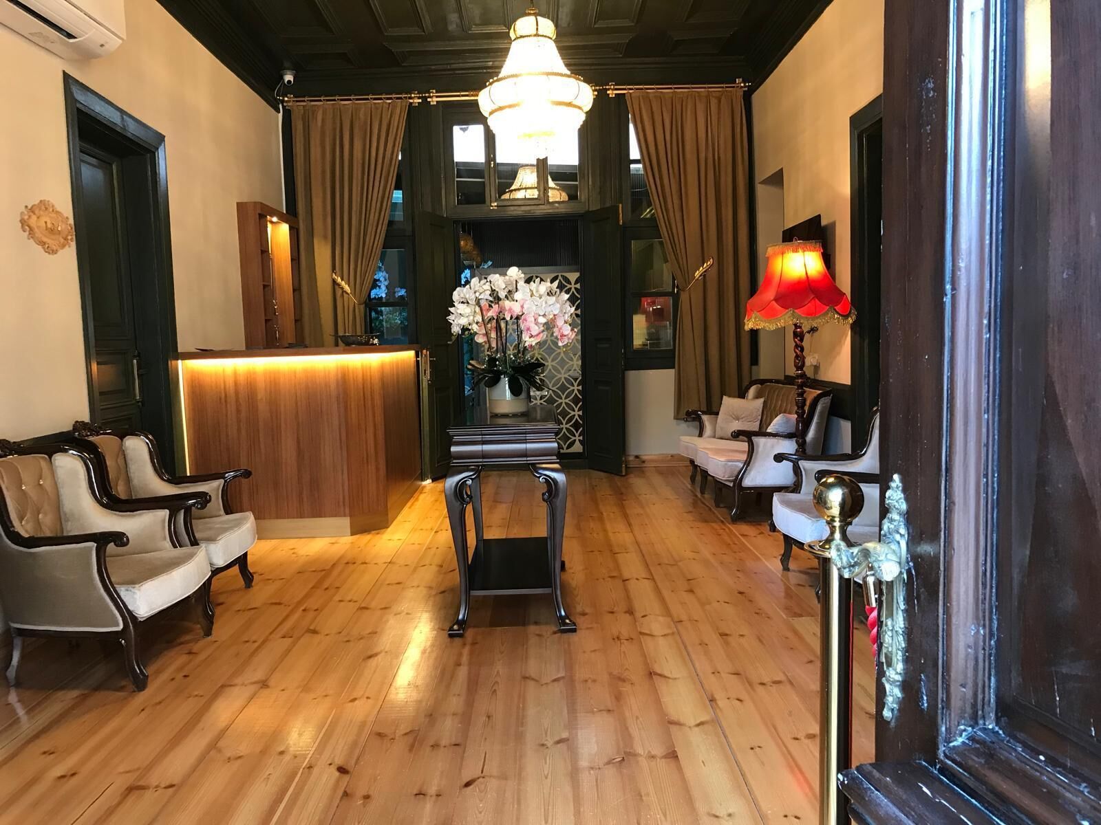 A hotel lobby with a reception desk, seating area, and a chandelier.