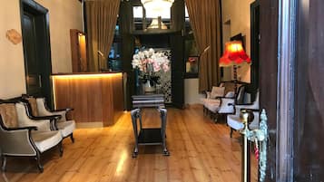 A hotel lobby with a reception desk, seating area, and a chandelier.