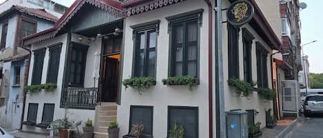 A building with multiple windows, a balcony, and potted plants.
