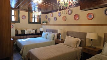 A hotel room with two beds, a chandelier, and decorative plates on the wall.