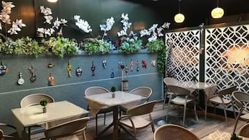 An indoor dining area with tables and chairs, decorative wall art, and hanging lights.