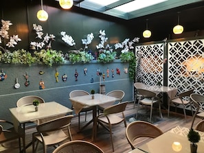 Un comedor interior con mesas y sillas, arte decorativo en las paredes y lámparas colgantes.