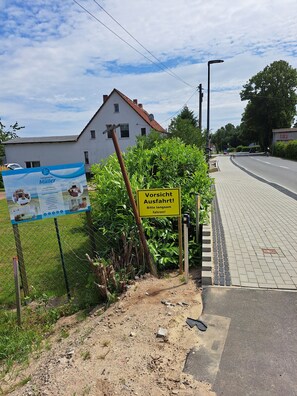 A road with a yellow sign and a white building in the background. - Müller Vacation Rental (Zirkow)