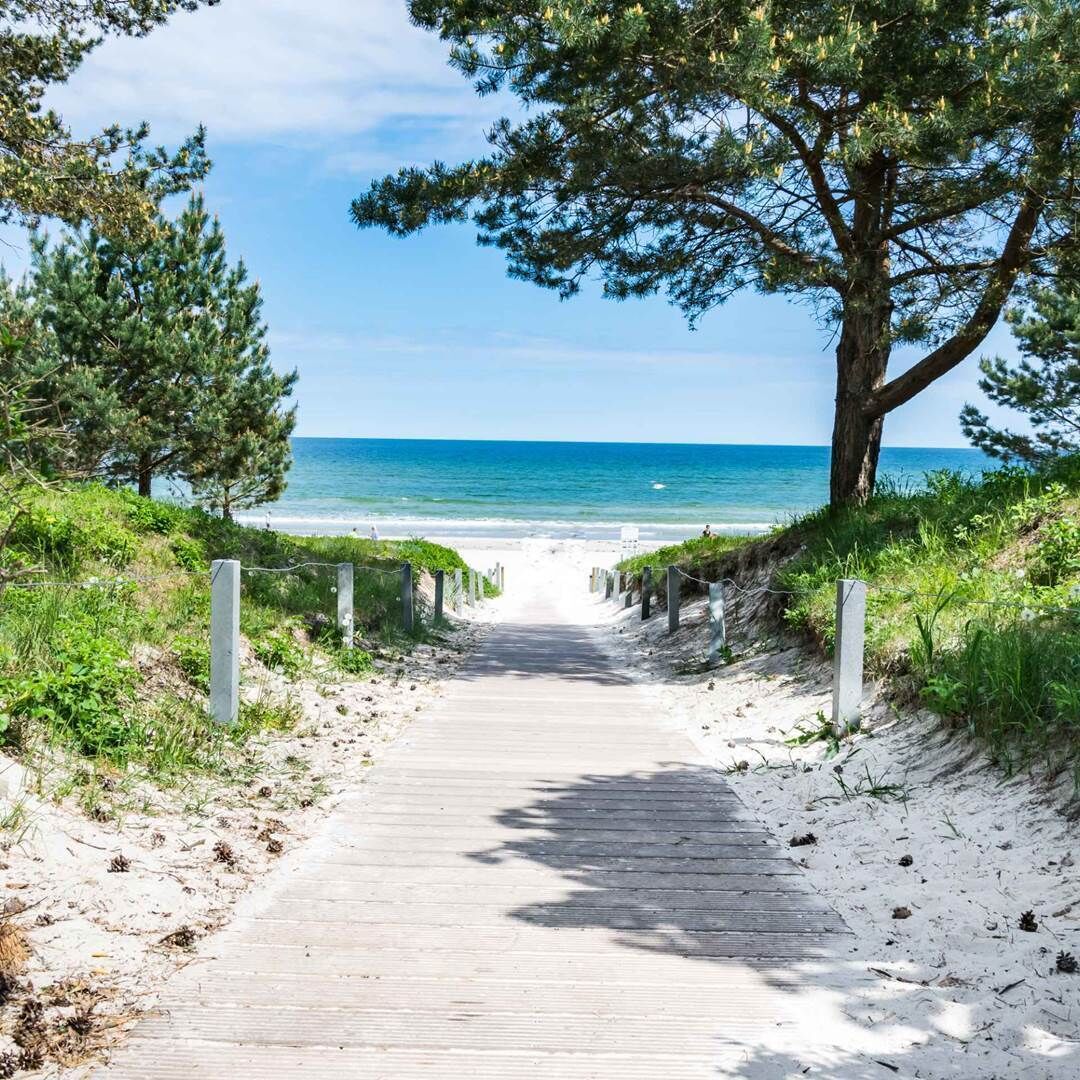 A wooden pathway leading to a beach with a clear view of the ocean.