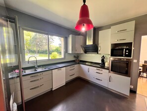 A modern kitchen with a window, stainless steel appliances, and a red pendant light. - Grand French Family Holiday Home (Saint-Germain-sur-Bresle)
