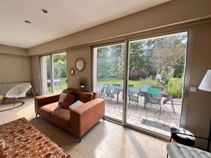 A spacious living room with a large sliding glass door leading to an outdoor patio area. - Grand French Family Holiday Home (Saint-Germain-sur-Bresle)