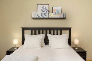 A neatly made bed with white linens and two pillows, flanked by two bedside tables with lamps, and a wall-mounted shelf above with framed artwork and a motivational quote. - Eco friendly holiday home with pool (Pula)