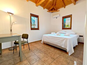 A bedroom with a bed, a desk, a chair, and two windows. - Emmelia Stone Maisonette: Panoramic Sea View (Kalamata)