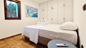 A hotel room with a bed, a small table, a window, and a painting on the wall. - Emmelia Stone Maisonette: Panoramic Sea View (Kalamata)