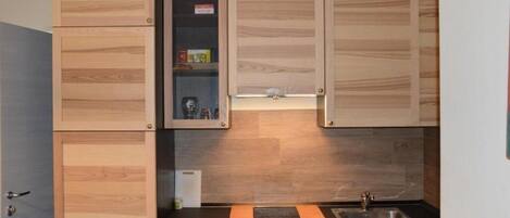A kitchen with wooden cabinets, a black countertop, and a stainless steel sink.