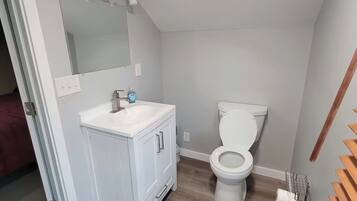 Ein Badezimmer mit weißem Waschtisch, Toilette und Duschbereich.