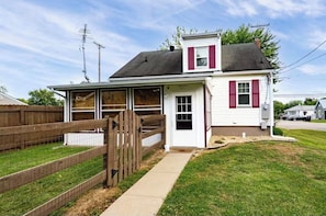 Einbungalow mit Veranda, kleiner Garage und umzäunter Garten.