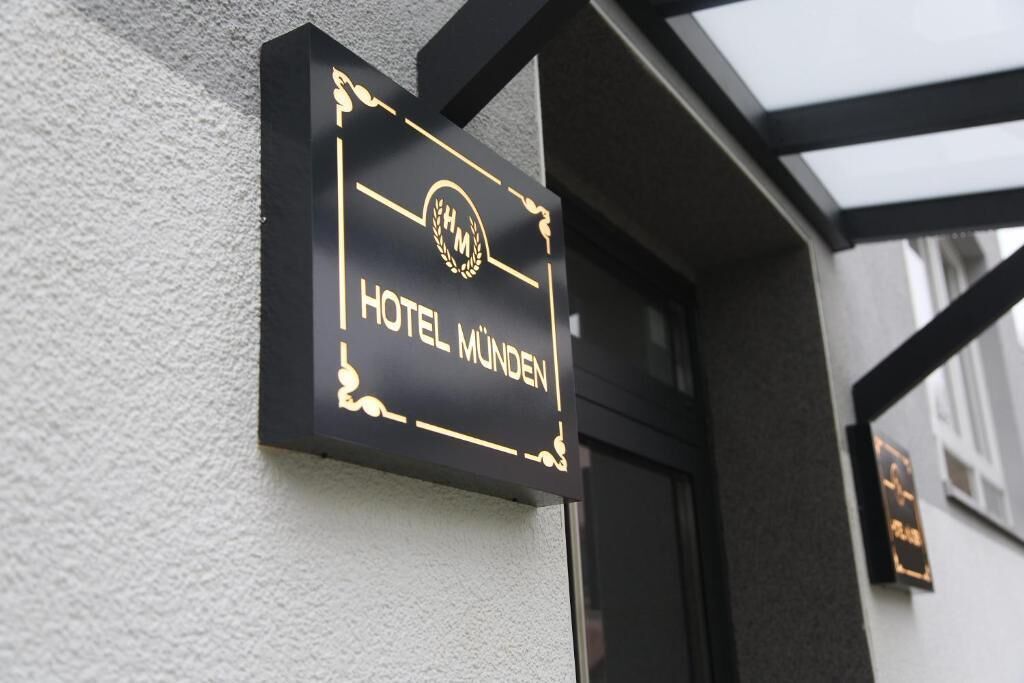 Une enseigne noire avec des lettres dorées indiquant « HÔTEL MÜNDEN ».