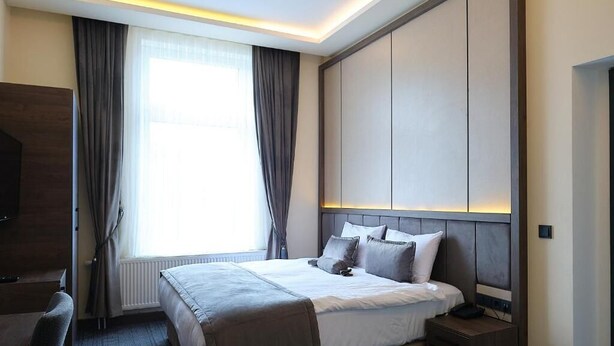Habitación de hotel con cama, mesita de noche y televisión.