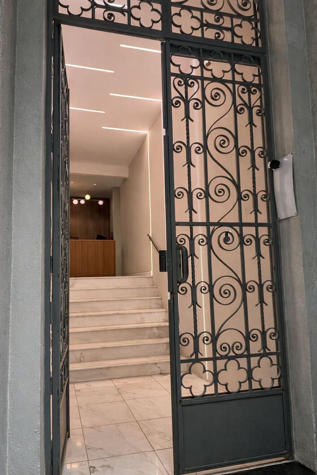 A hallway with a decorative metal gate, a staircase, and a reception area in the background.