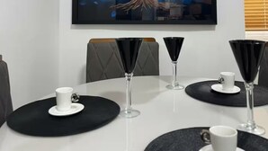 Ein Esstisch mit schwarzen Platzsets, weißen Tassen und einem farbenfrohen Gemälde eines Baumes an der Wand.