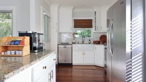 A modern kitchen with white cabinetry, a stainless steel refrigerator, and a coffee maker on the counter. - Beautiful Avondale Bungalow, Downtown BHAM a 5 min drive, UAB & Airport 10 mins. (Birmingham)