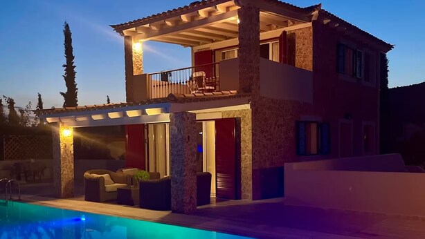 Ein zweistöckiges Haus mit Pool, Sitzgelegenheiten im Freien und einem Balkon.