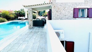 Eine moderne Villa mit Swimmingpool, Sitzgelegenheiten im Freien und einer Steinfassade.