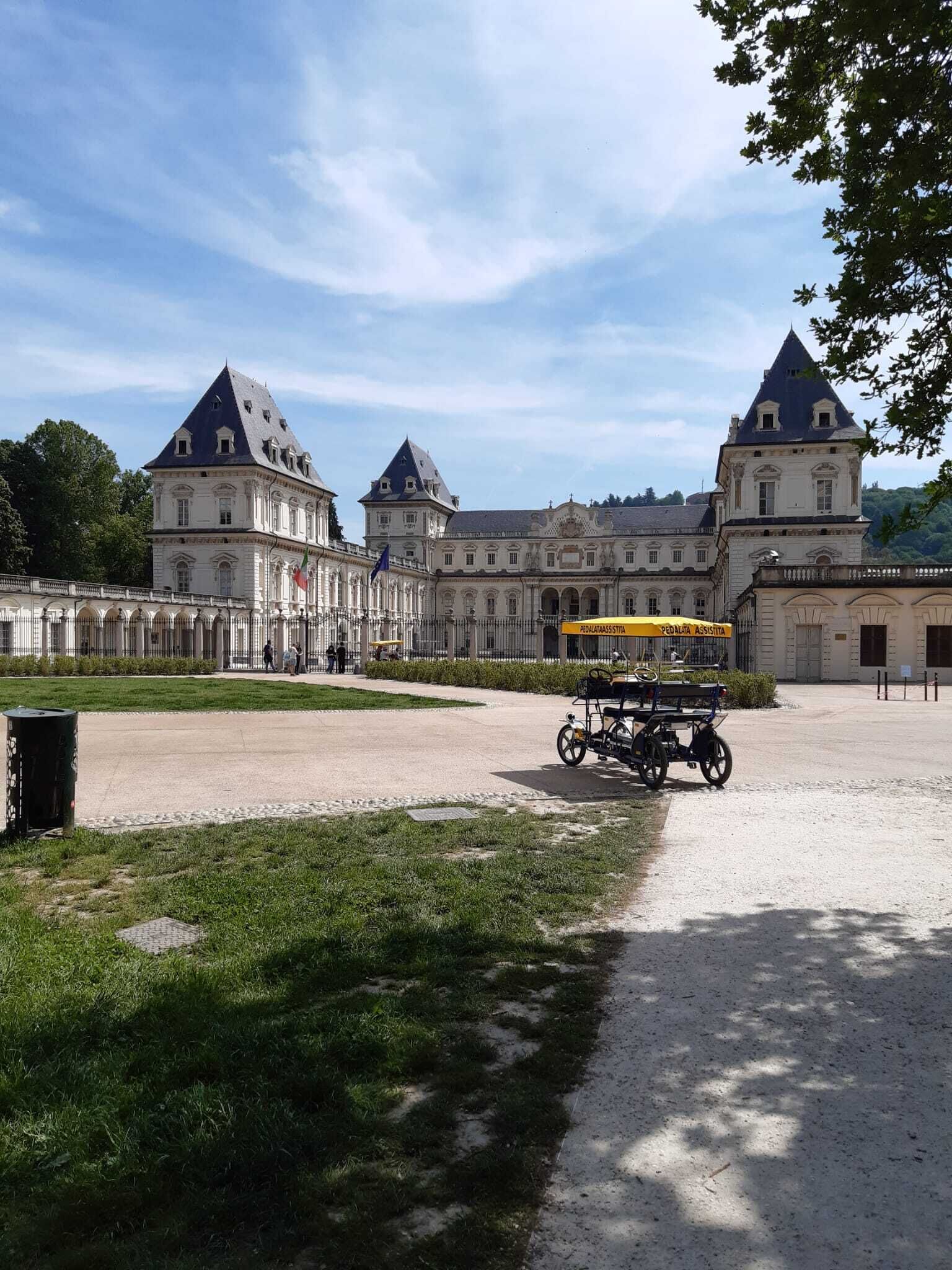 A large historic building with multiple towers and a paved courtyard.