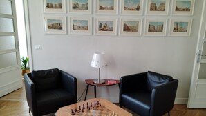 A room with a chessboard, two black armchairs, a lamp, and framed pictures on the wall. - Vacation in Turin, just a few minutes from downtown in a lively, multicultural neighborhood (Torino)