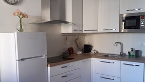 A modern kitchen with white cabinets, a stainless steel microwave, and a built-in oven. - Vacation in Turin, just a few minutes from downtown in a lively, multicultural neighborhood (Torino)