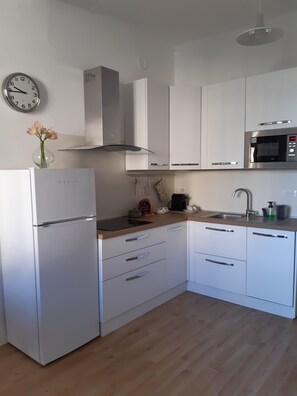 Eine moderne Küche mit weißen Schränken, einer Edelstahl-Mikrowelle und einem eingebauten Backofen.