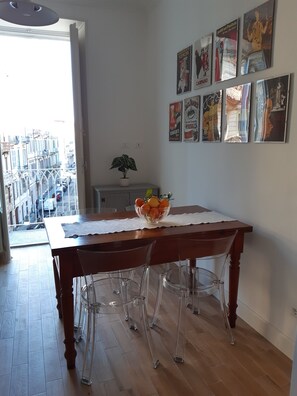 A dining area with a wooden table, clear chairs, a fruit bowl, and wall art. - Vacation in Turin, just a few minutes from downtown in a lively, multicultural neighborhood (Torino)