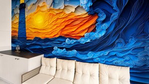 Una habitación con un mural de un faro y olas, un sofá con cojines y una pequeña mesa con un adorno.