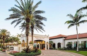 A hotel entrance with a sign reading 'Naples Key Club,' palm trees, and a paved driveway. - Luxury 3 BR at Resort Near Beach and Downtown-  (Naples)