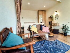 Un salon avec un canapé, des fauteuils, une table basse, un miroir et une plante en pot.