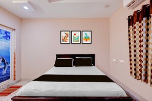 Un dormitorio con cama, ventana con vista y tres obras de arte enmarcadas en la pared.