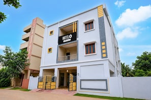 A modern hotel with a prominent 'HOTEL' sign, a gated entrance, and a balcony on the second floor.