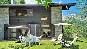 Een modern huis met een terras, buitenmeubels en een stenen muur.