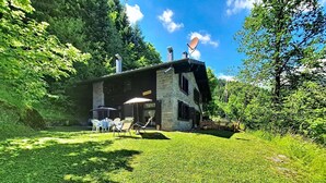 Een stenen gebouw met een schotelantenne, terras en een gazon.