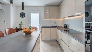 Et moderne køkken med en lang bordplade, skabe og et spiseområde med stole og et bord.